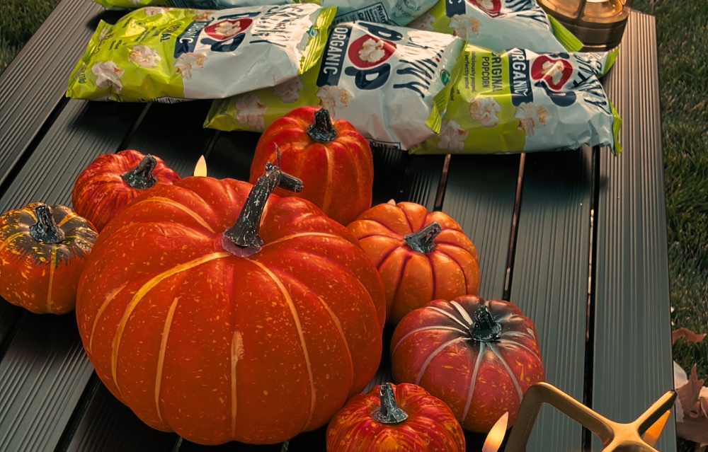 A table with popcorn, pumpkins and lanterns.